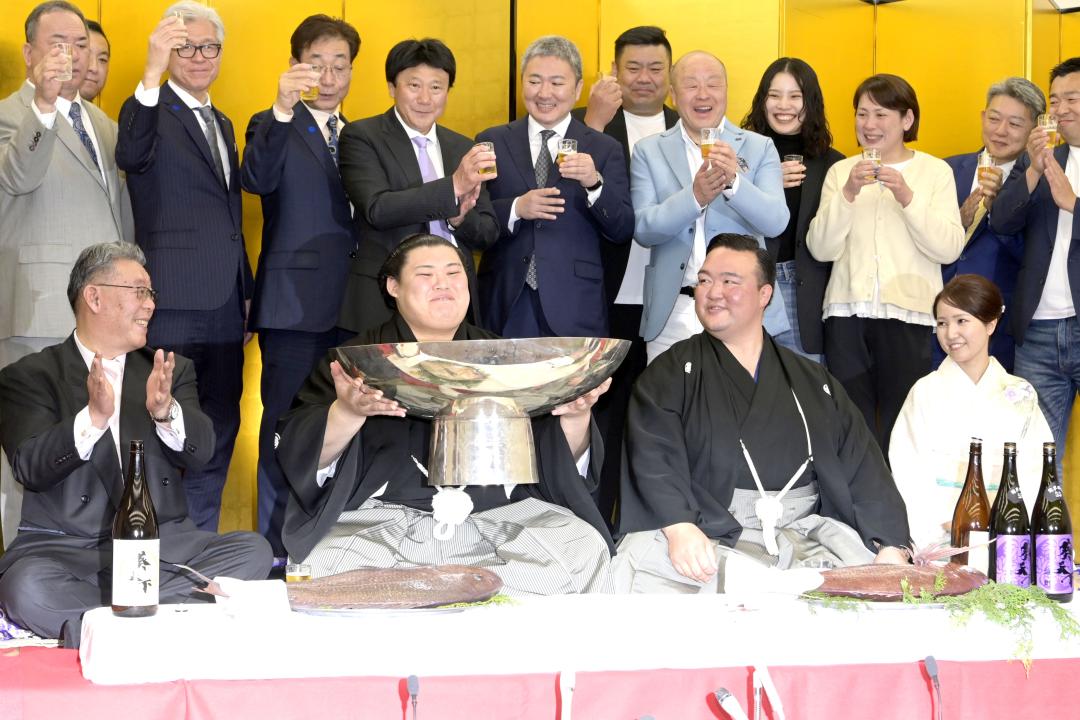 優勝して祝い酒を飲む大の里(左から2人目)を見つめる二所ノ関親方(右から2人目)=23日午後7時35分、大阪府大東市