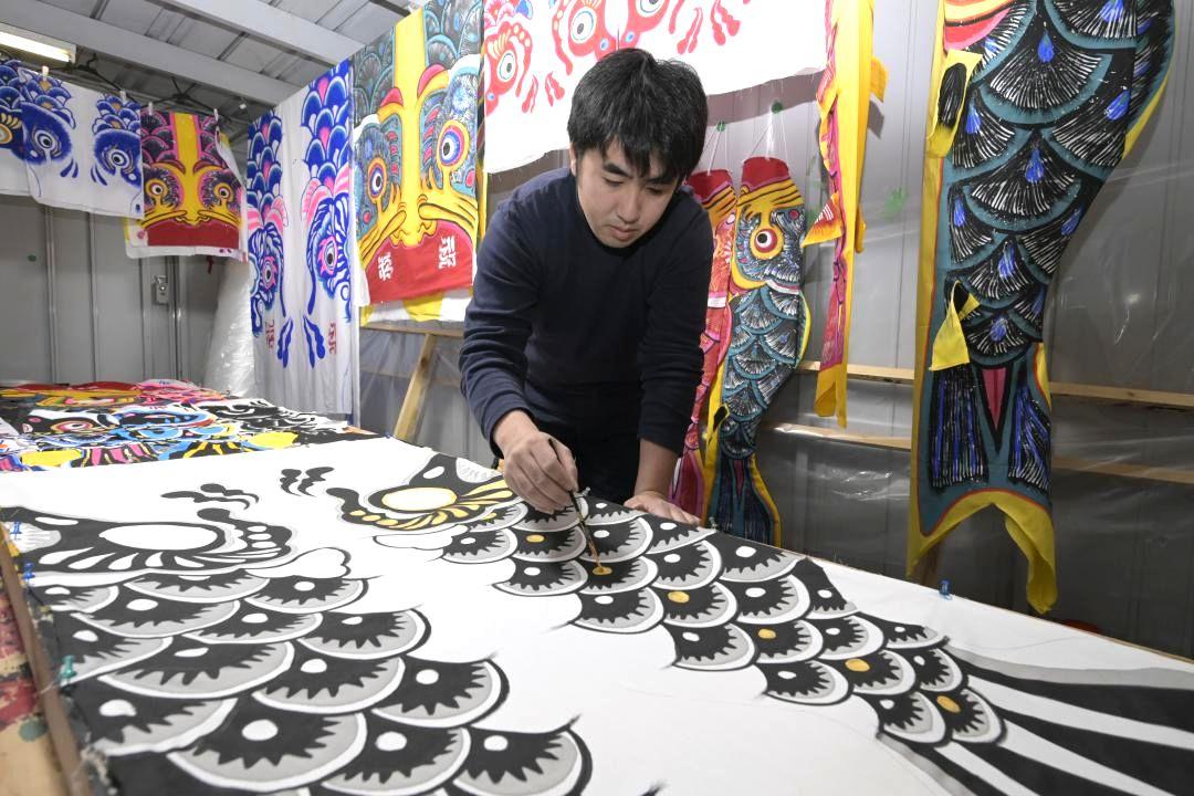 こいのぼりの色付け作業に追われる荒野麟太郎さん=潮来市洲崎