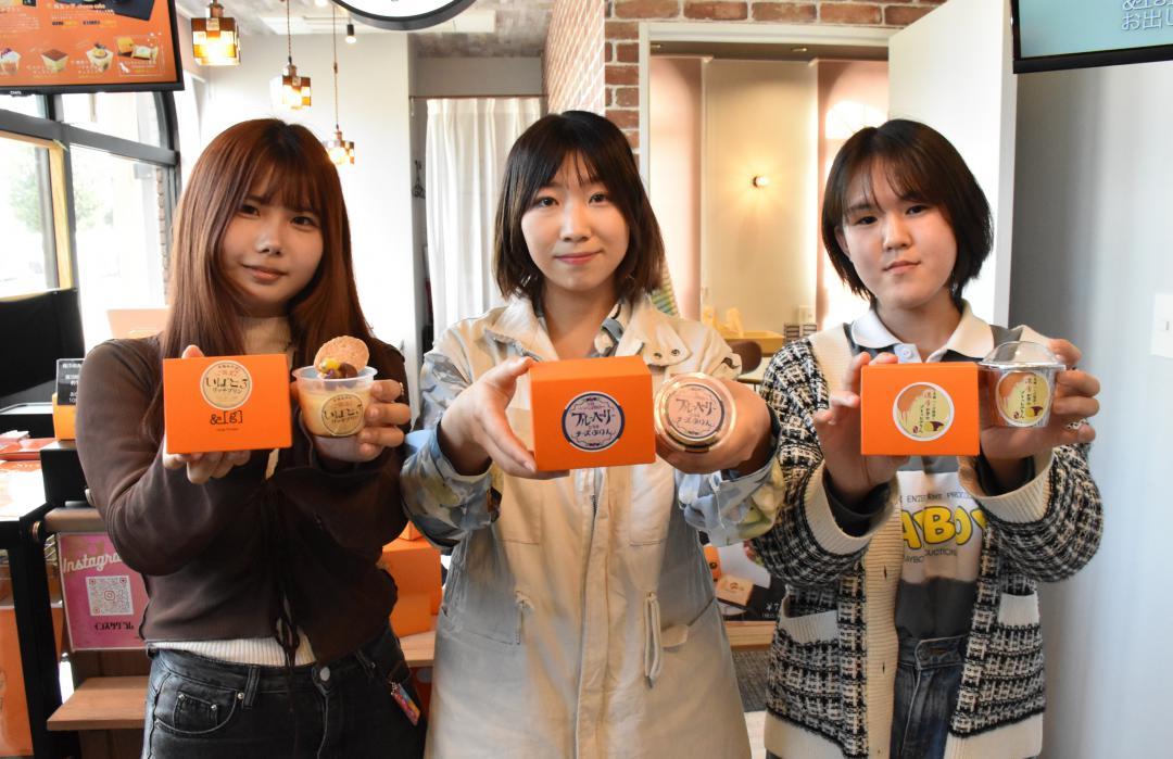 採用されたパッケージデザインの商品を持つ(左から)吉田有希さん、吉野侑良さん、田麦梨々花さん=つくば市内