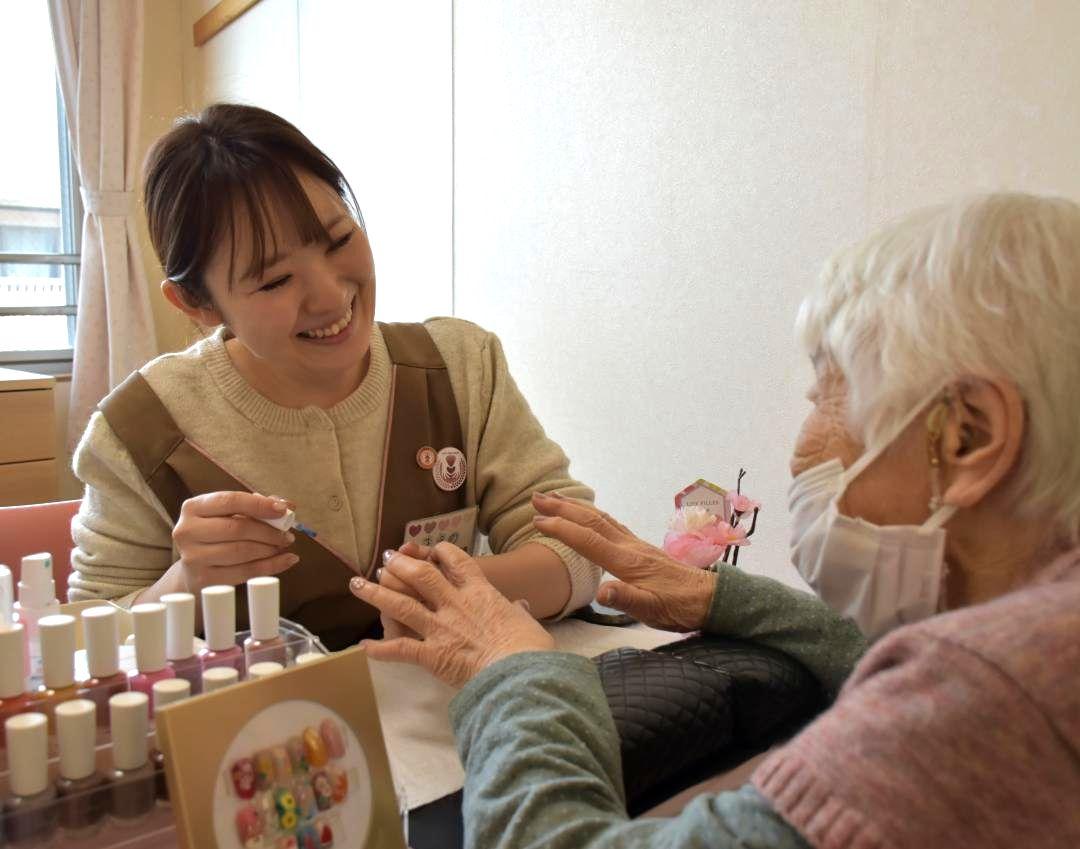 高齢者介護施設に出向き利用者にネイルサービスを行う前野美穂さん(左)=2月、鉾田市鉾田
