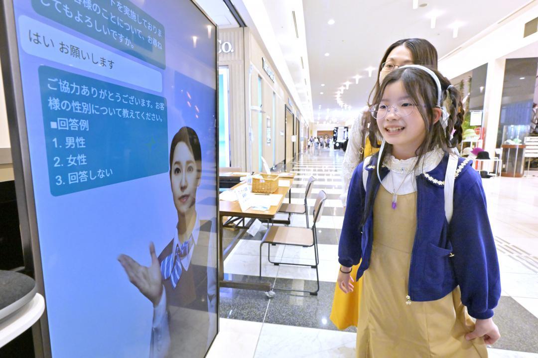 AIアバターが質問するアンケート内容に回答する親子=水戸市泉町