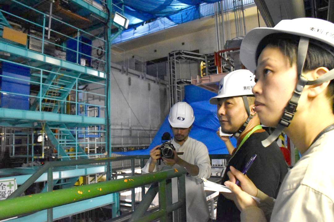 高エネ研の測定器を見学する(右から)岩竹理恵さん、片岡純也さん=つくば市大穂
