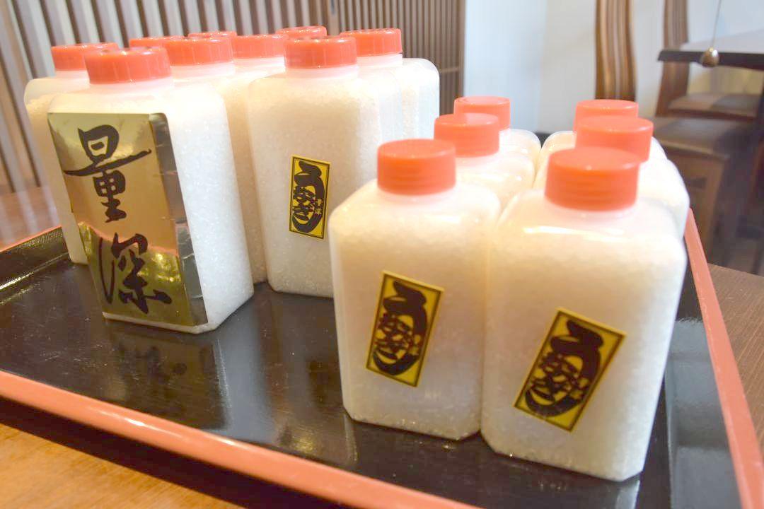 馬場万作さんらがプラスチックケースに詰め来店者に手渡しているコメ=笠間市笠間