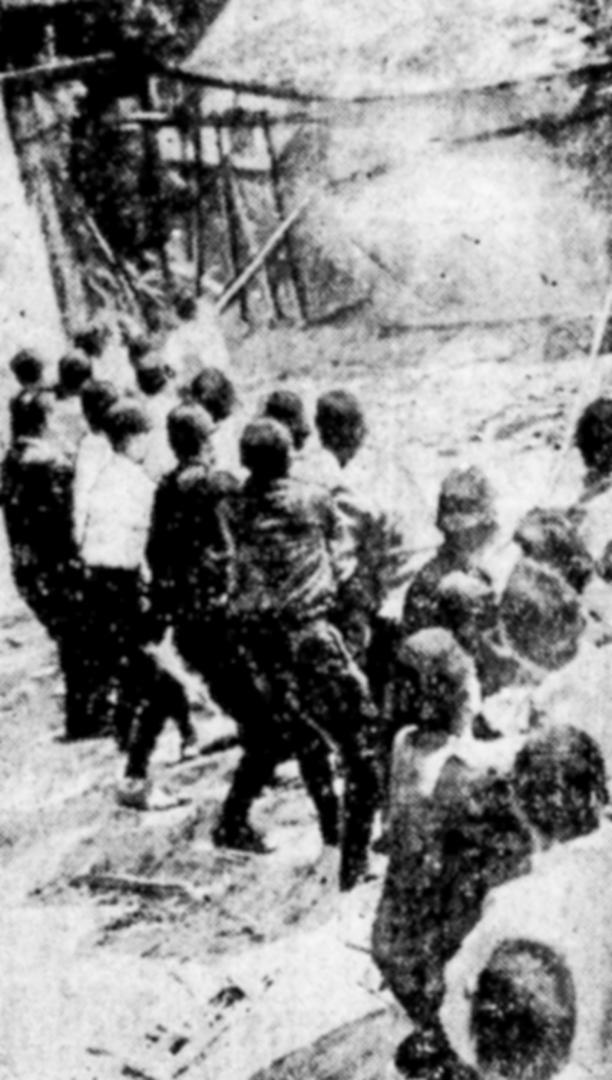 建物の取り壊しに協力する警察官。柱につなげた綱を引いているとみられる(1945年4月13日付京都新聞から)