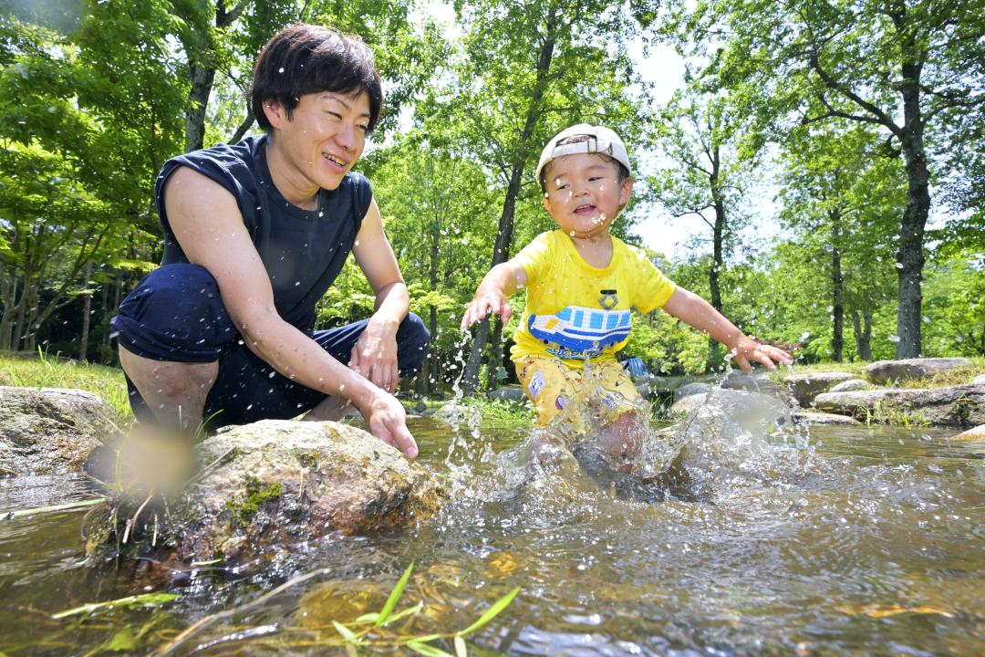 今年初の真夏日となり、水遊びを楽しむ親子=20日午前、水戸市千波町
