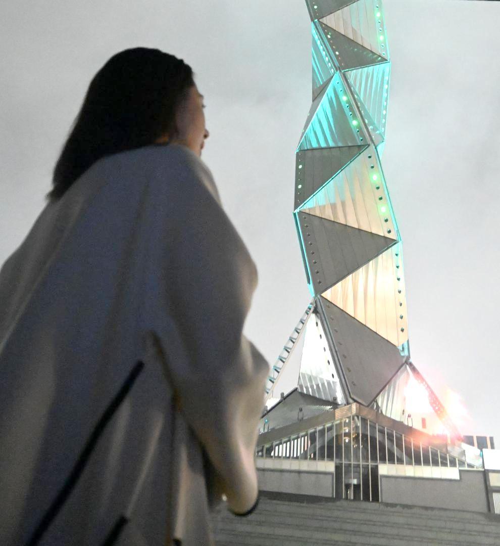 緑色にライトアップされた水戸芸術館タワーを見つめる菊池昌子代表=水戸市五軒町
