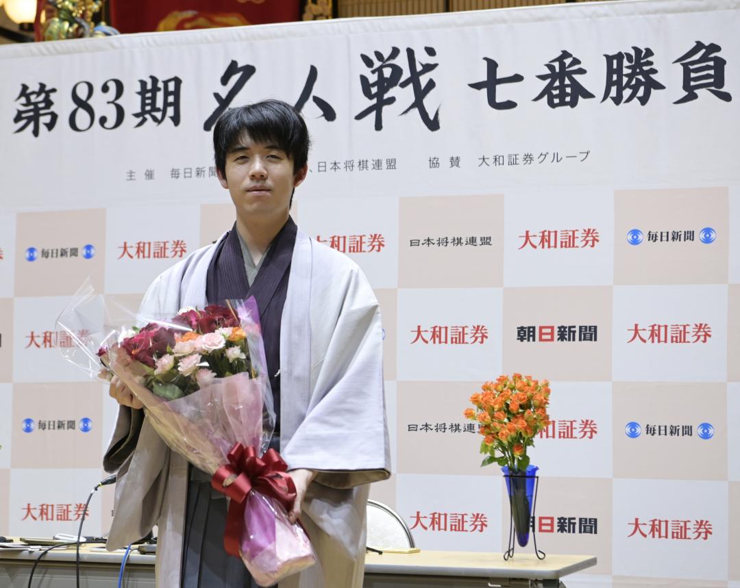 名人戦で3連覇し、終局後の記者会見で花束を手にほほ笑む藤井聡太名人=31日午前1時、古河市横山町