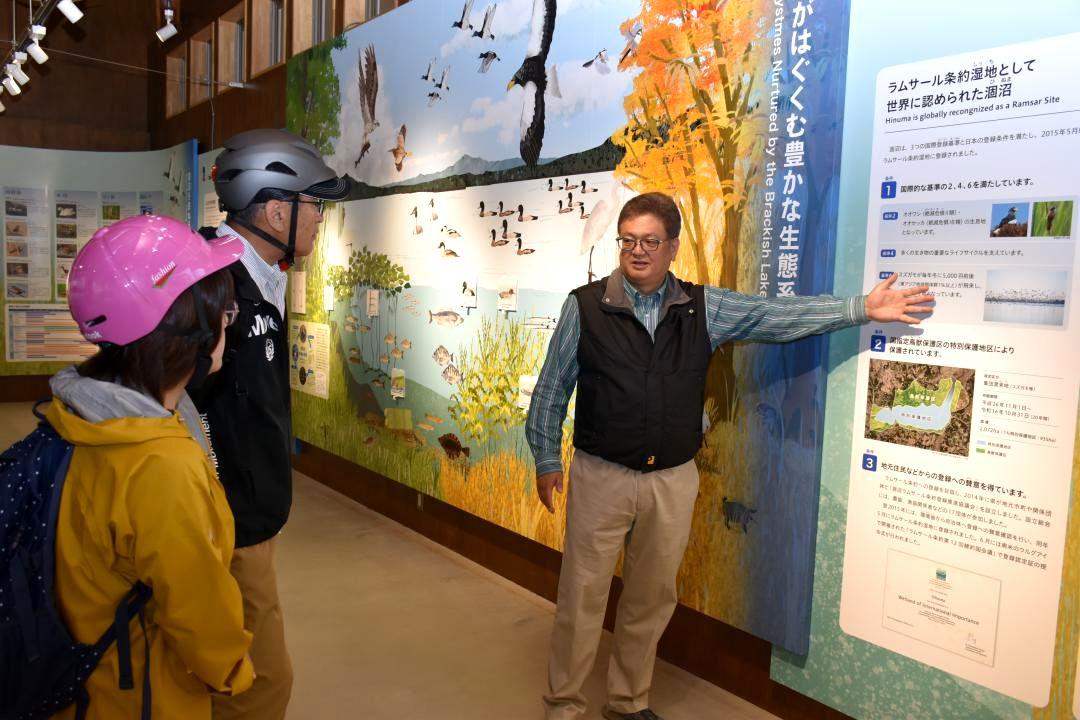 涸沼水鳥・湿地センターの展示施設で専門員から涸沼の解説を受ける来館者=茨城町下石崎