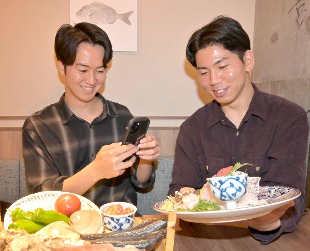 スマートフォンでイチ押しメニューの動画を撮影する鎌田晃介さん(左)、斎藤聖さん=つくば市吾妻