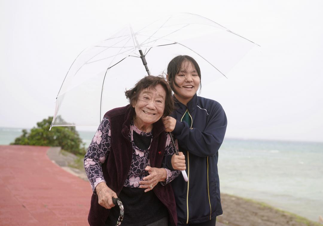 家族でよく遊びに来る公園で沖縄戦について語り合う大城静子さん(左)と孫の侑生さん。晴れている時は海の向こうに渡嘉敷島が見えるという=3月13日、沖縄県糸満市・南浜公園(竹花徹朗撮影)
