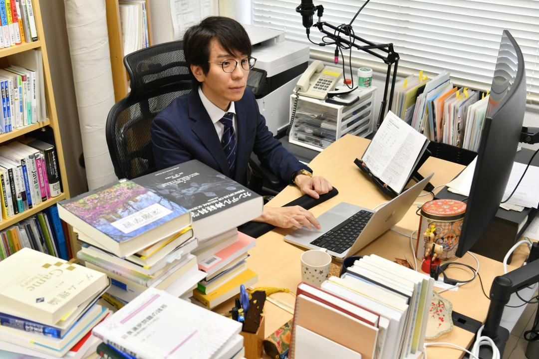 書籍に囲まれながら、人間の感性を理解するAI開発に取り組む筑波大の伊藤寛祥助教=つくば市春日