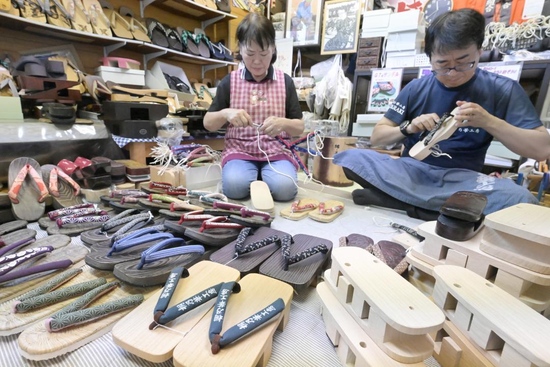 手際よく鼻緒を取り付けていく桐乃華工房の猪ノ原武史代表(右)ら=筑西市関本上