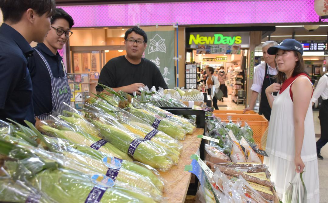 生産者と会話しながら野菜を選ぶ買い物客(右)=水戸市宮町
