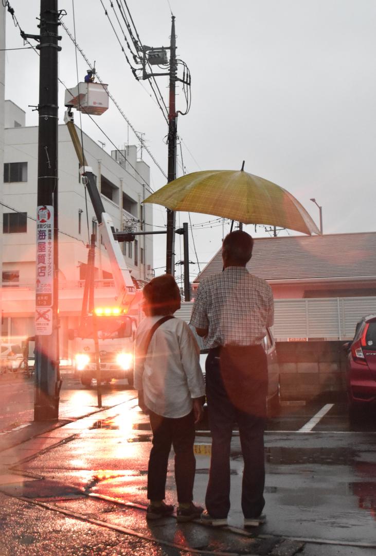電力の復旧作業の様子を見守る近所の住民=古河市東本町1丁目