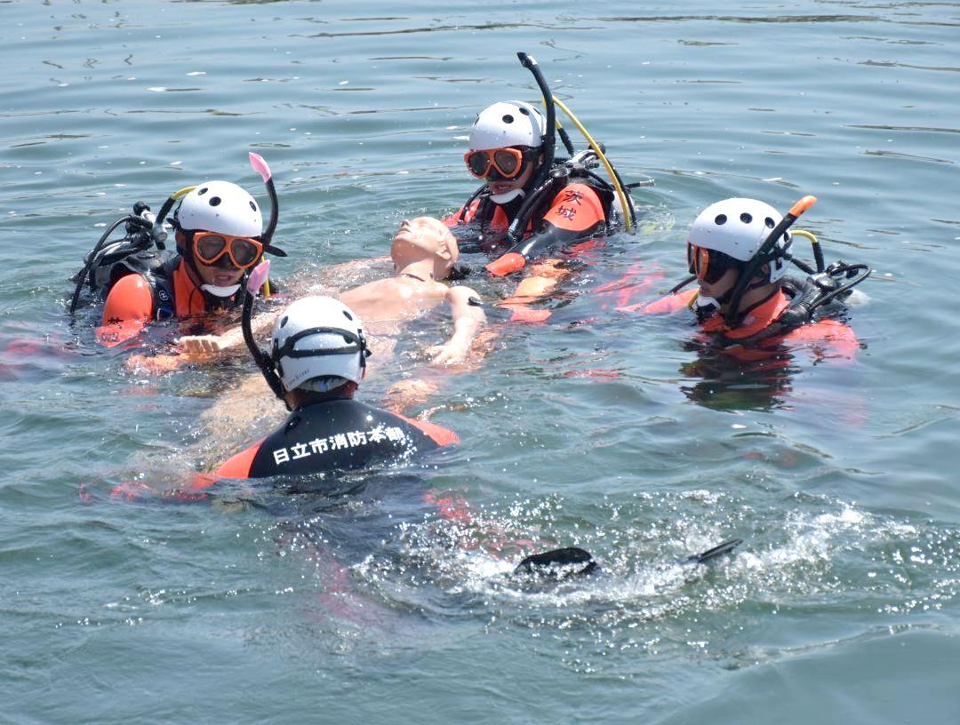 人形を海での水難者に見立て訓練する水難救助隊員=6月、日立市みなと町