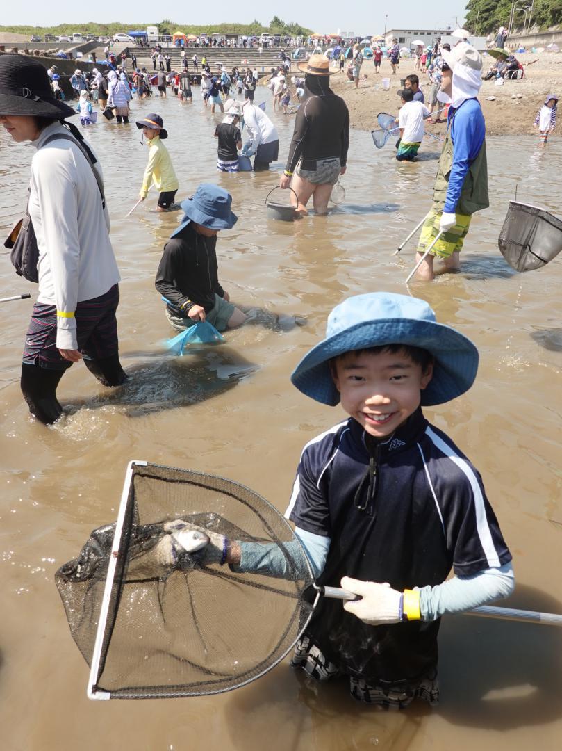 「姥の懐マリンプール」の水抜き調査イベントで魚を捕まえて喜ぶ参加者の少年=ひたちなか市殿山町
