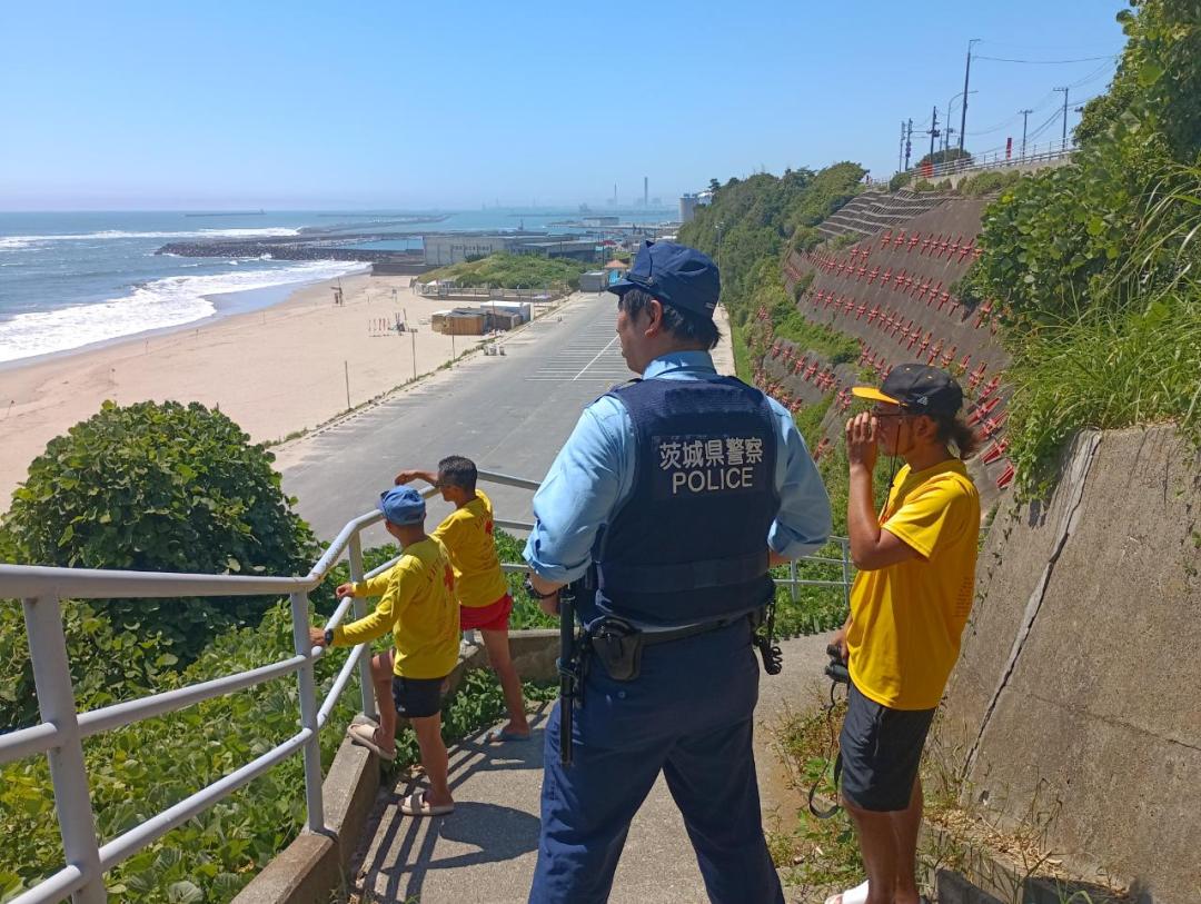 久慈浜から避難したライフセーバーと状況を見守る警察官＝日立市