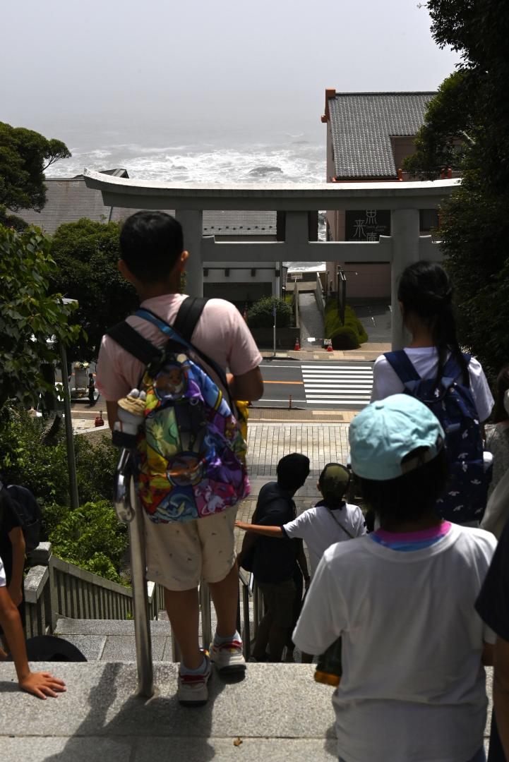 津波警報が発令され、高台に避難し海の様子を見つめる人たち=30日午前10時58分、大洗町磯浜町