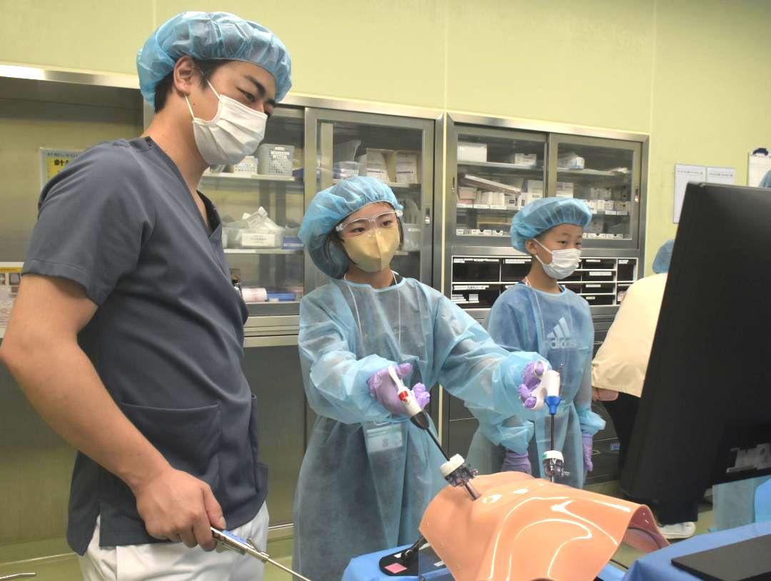 医師(左)からアドバイスを受け手術のシミュレーションを体験する参加者=神栖市知手中央
