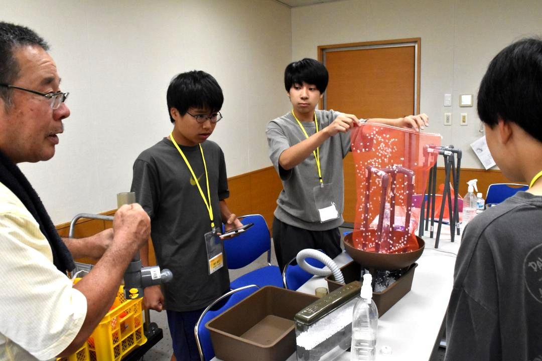 東京理科大の関陽児教授(左端)から火山噴火の仕組みを学ぶ生徒ら=5日、つくば市竹園