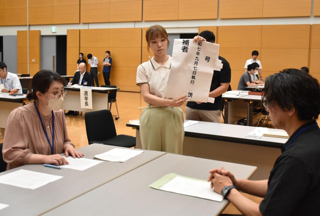 選挙の「七つ道具」を候補者役(右)に説明する県選管職員=県庁