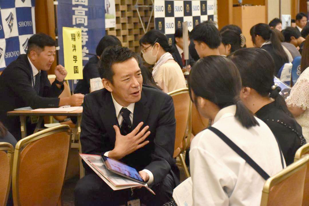 県内の私立高が集まる私学フェアで、学校担当者から説明を受ける中学生と保護者ら=水戸市宮町

