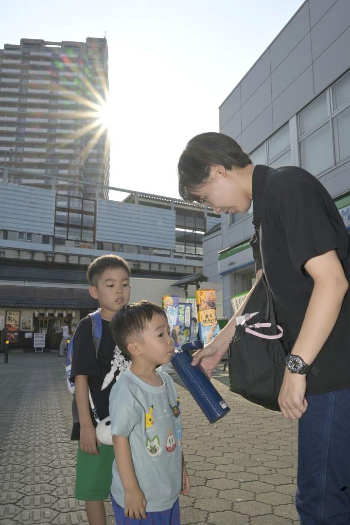 古河市で気温40.6度を観測した5日、JR古河駅前でバス待ちをしながら、水分補給する子どもたち。熱中症予防で水分補給は大きなポイントとなる=同市東
