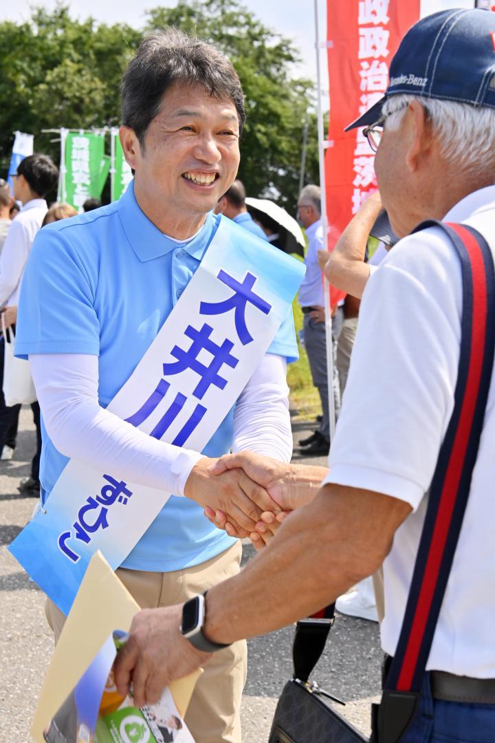 県知事選の街頭演説で有権者と握手を交わす大井川和彦氏(左)=28日午後、かすみがうら市上土田