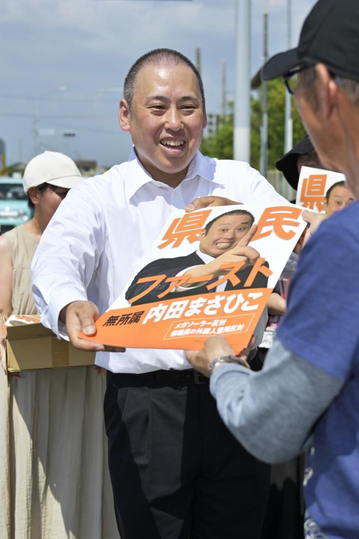 ポスター貼りを手伝うボランティアに完成したポスターを手渡す内田正彦氏=30日午後、土浦市内
