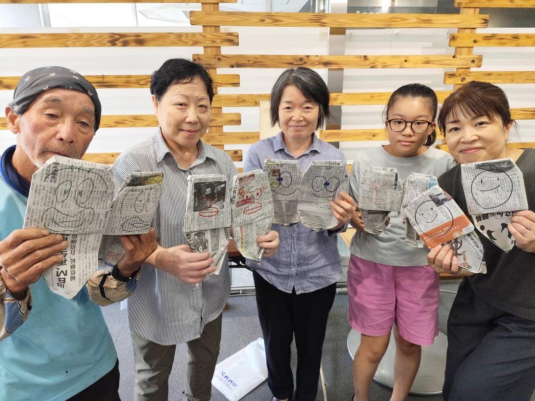 新聞紙で作ったスリッパを手にする参加者=水戸市南町2丁目の茨城新聞みと・まち・情報館