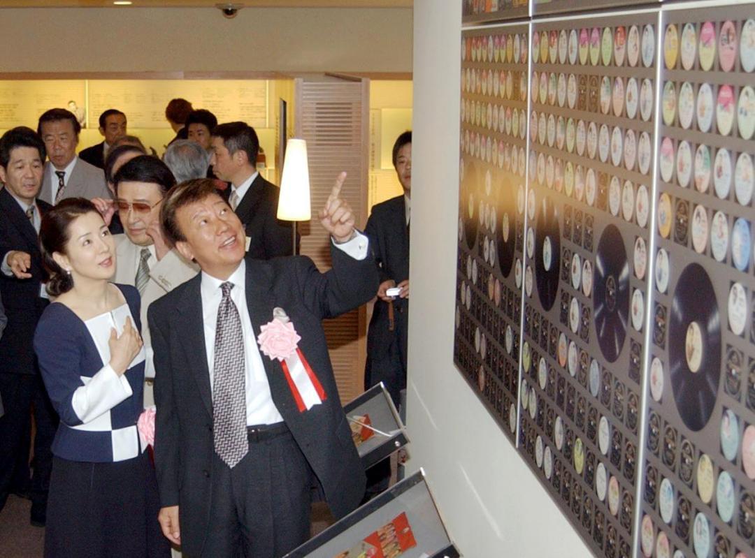 吉田正音楽記念館が開館し、館内に展示されたレコードジャケットなどを懐かしそうに見て回る橋幸夫さん(手前右)と吉永小百合さん(同左)=2004年4月27日、日立市宮田町