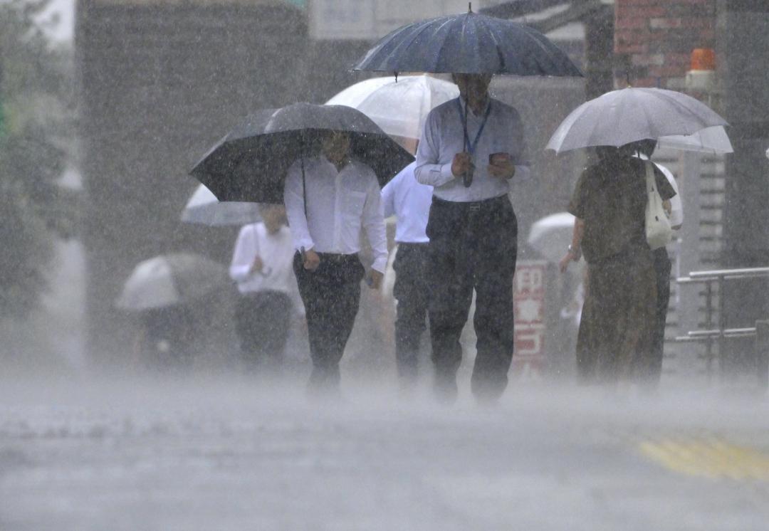 強い雨が路面に打ち付ける中、傘を差して歩く人たち=5日午後0時8分、水戸市南町