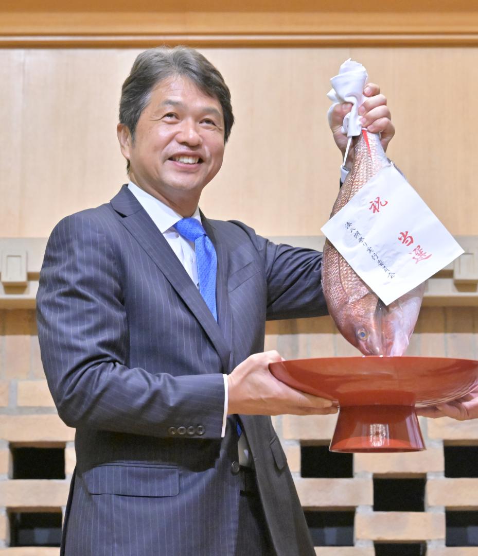 県知事選で３回目の当選が確実となり、支持者から受け取ったタイを掲げる大井川和彦氏＝７日午後８時４分、水戸市内