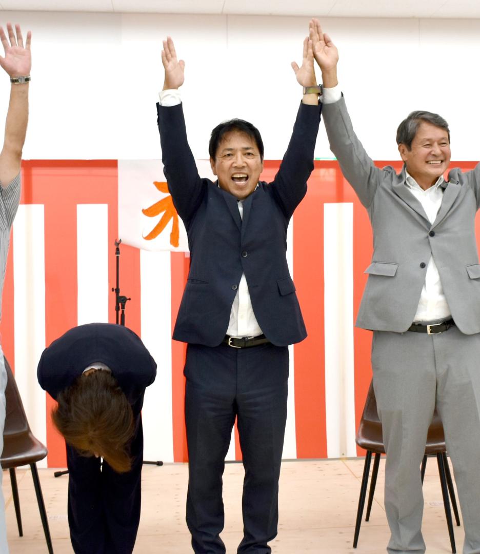 初当選を決めて支持者らと万歳する高須敏美氏(中央)=7日午後10時20分ごろ、行方市玉造甲