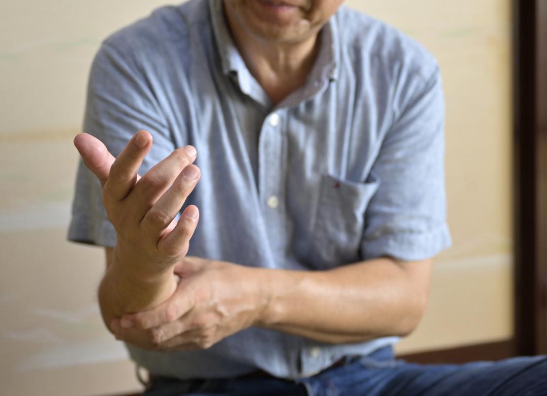 右腕の傷に触れながら、事件当時の状況について話す被害者の男性=水戸市内