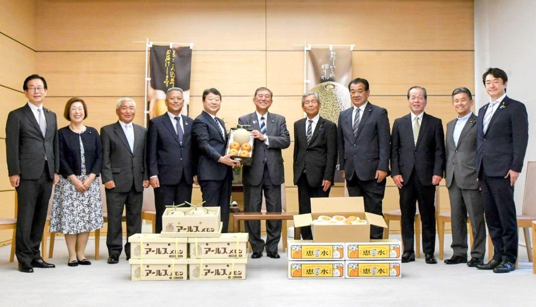 石破茂首相(中央)にナシとメロンを贈る野村勇八千代町長(左から5人目)ら=首相官邸
