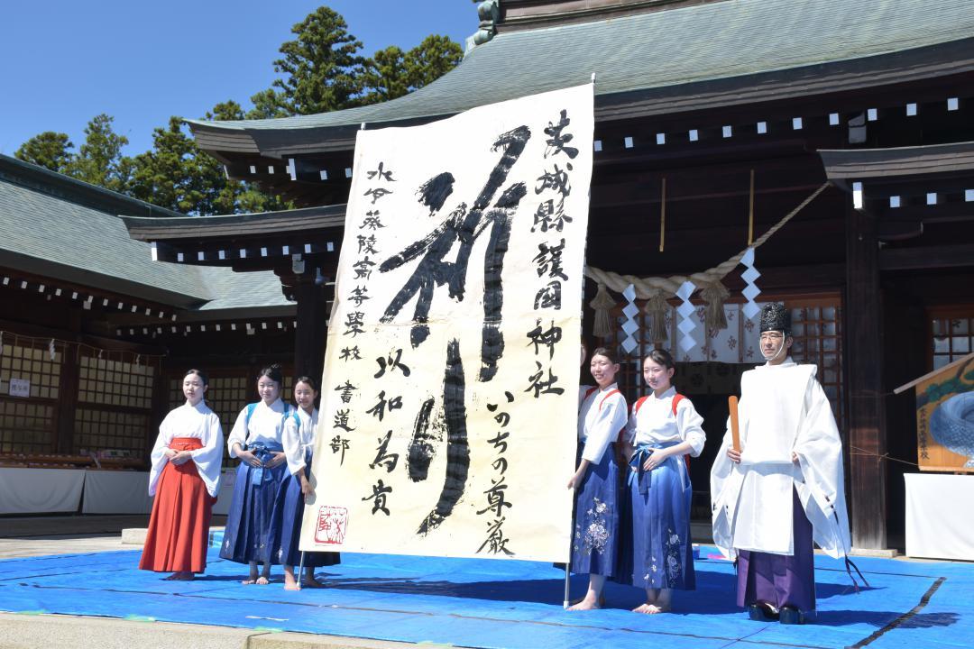 国連で定める「国際平和デー」に合わせ、平和を祈願して揮毫した水戸葵陵高校書道部の4人と、同神社の林竜司宮司(右)=県護国神社
