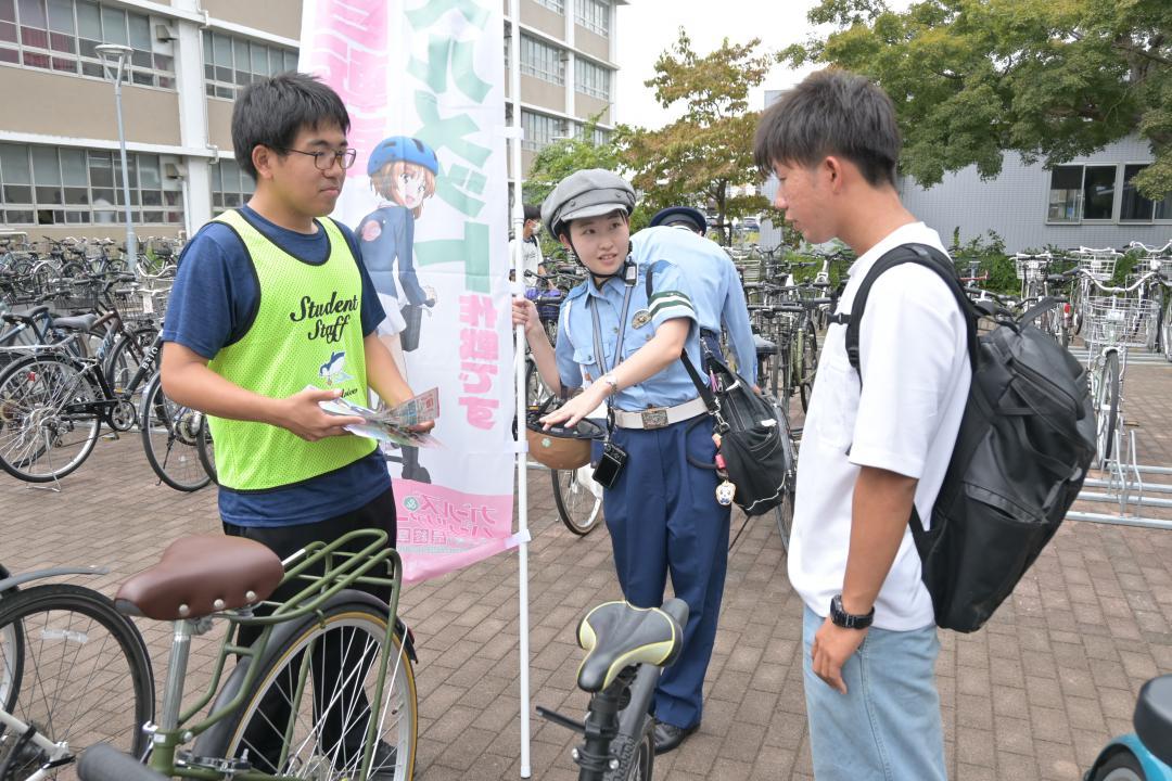 自転車を利用する学生に安全利用を呼びかける警察官とボランティアの学生=水戸市文京

