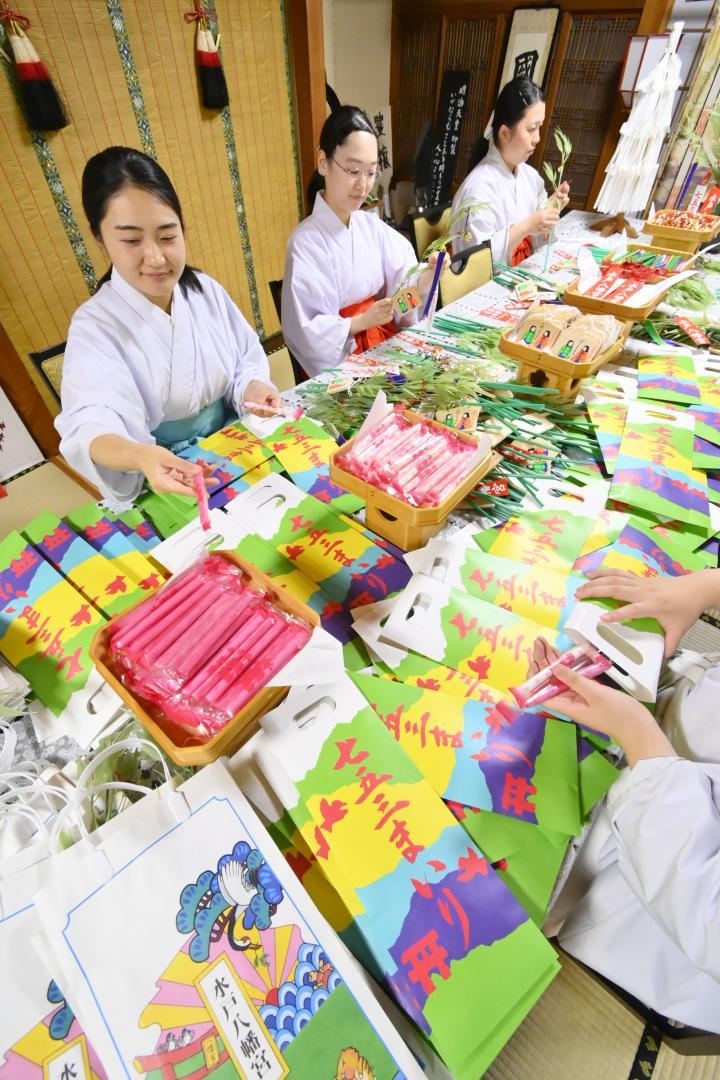 七五三に向けて千歳あめを袋に入れたり、縁起物を作ったりする神職と巫女=水戸市八幡町