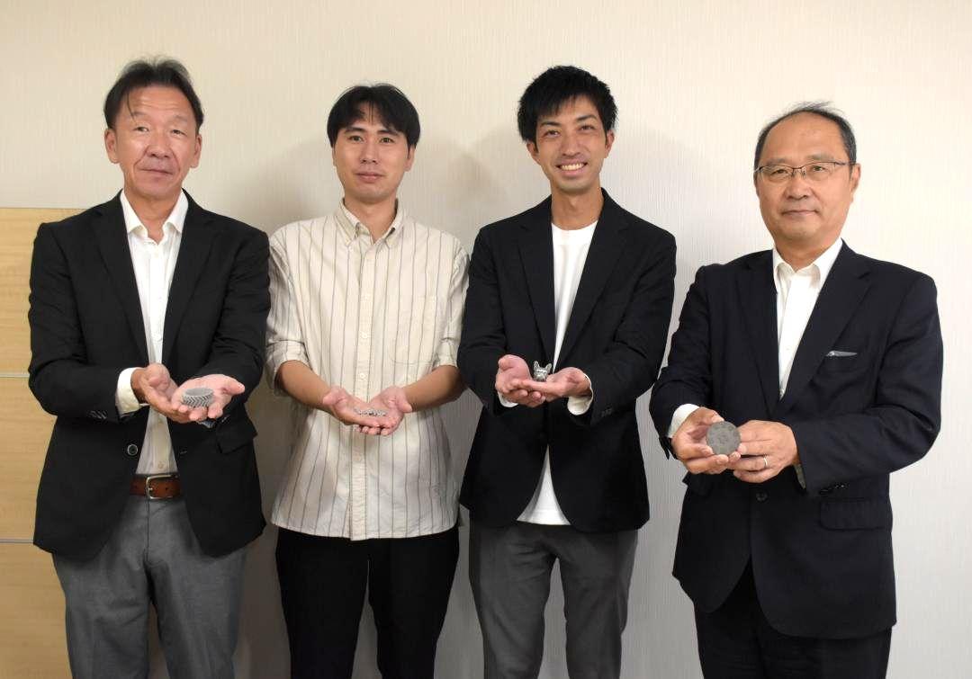 3Dプリンターで製作した金属製の試作品を手にする坂場商店の坂場光治社長(右)ら=水戸市浜田
