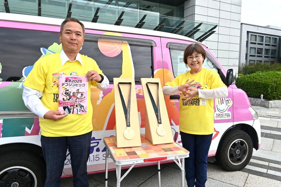 東京2025デフリンピックで選手に贈られる金メダルのレプリカ(中央)を披露する県聴覚障害者協会の吉沢馨会長(右)と水戸市聴覚障害者協会の松嶋清会長=県庁
