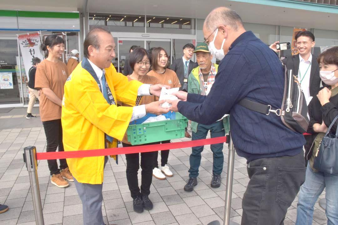 先着100人にけんちんまんを手渡す藤田謙二市長(手前左)=常陸太田市下河合町
