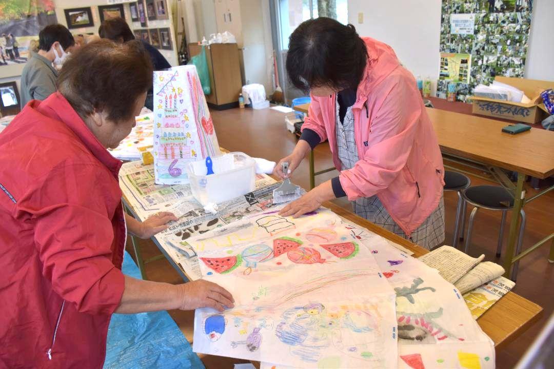 子どもたちが描いた絵をあんどんに取り付けられるように貼り合わせていった=常陸太田市西河内下町