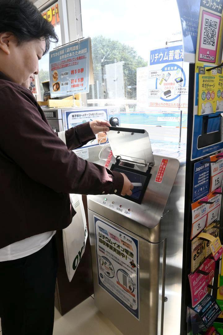 コンビニ店内の回収ボックスにモバイルバッテリーを入れる買い物客=守谷市松並