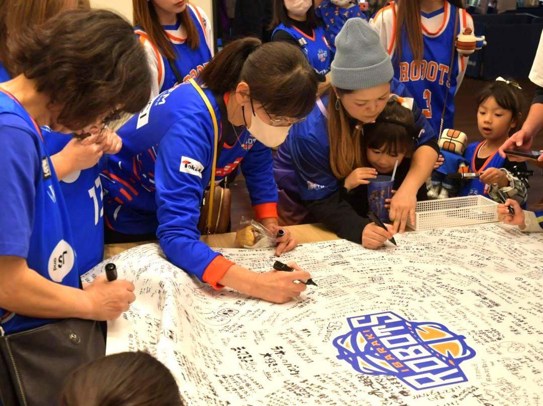茨城ロボッツ・平尾選手へのメッセージを書き込む来場者たち=かみす防災アリーナ