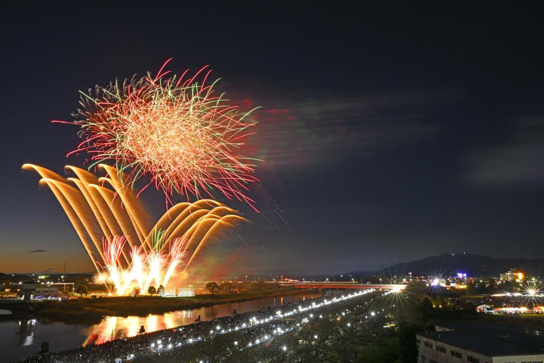 土浦全国花火競技大会で夕闇に打ち上がる花火。右奥には筑波山がそびえる=1日、土浦市の桜川畔