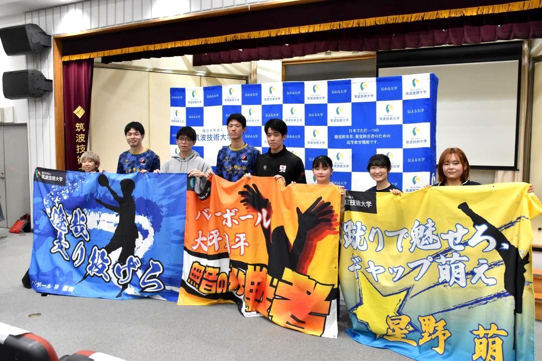 デフリンピックの応援用横断幕を持つ出場選手と学生=つくば市天久保