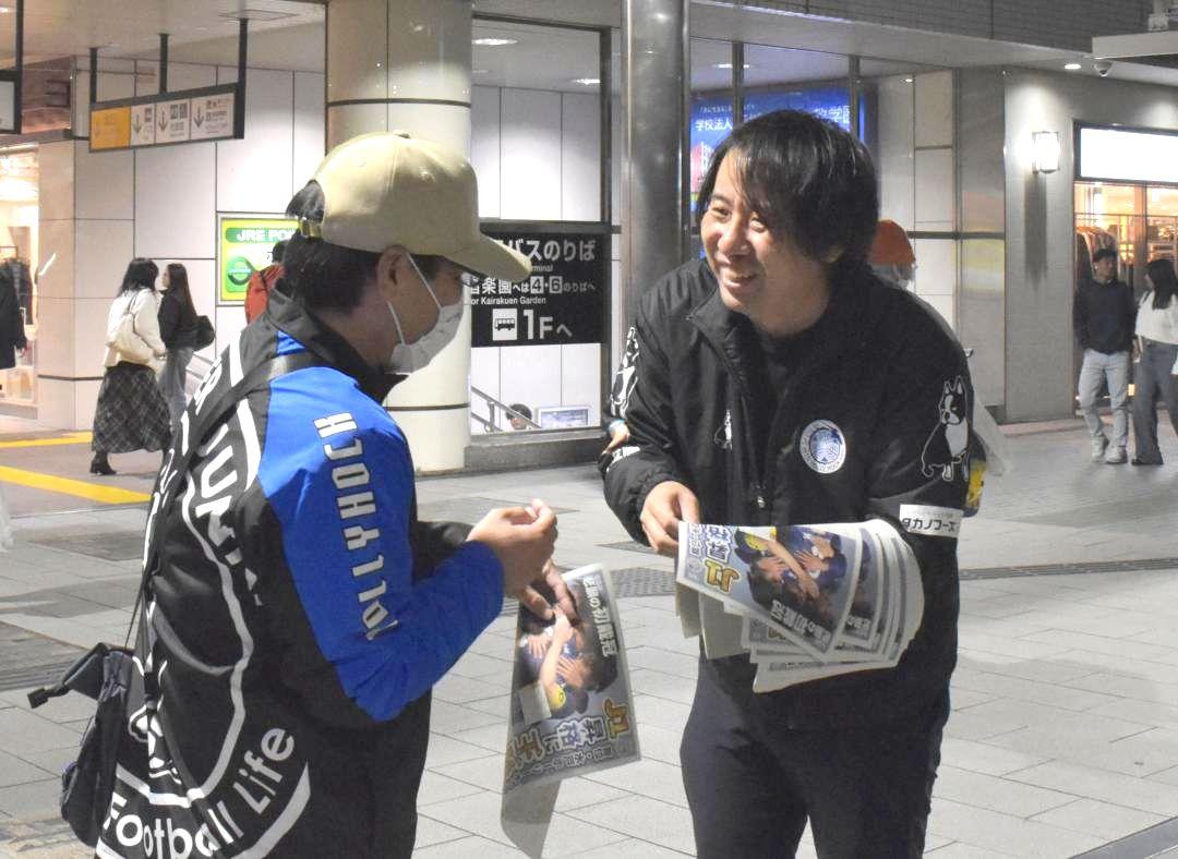 J2水戸の昇格を後押ししようと「号外」チラシを配るスタッフ(右)=JR水戸駅北口