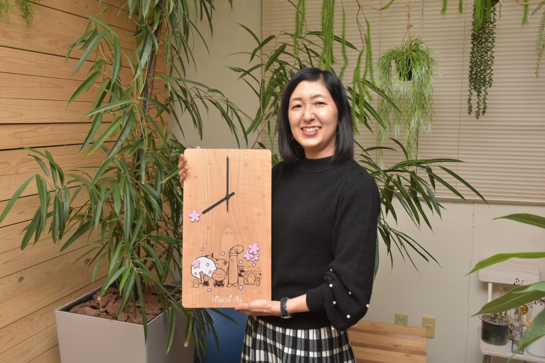 平和通りの桜の木を活用した時計を持つ福地美喜副社長=日立市内