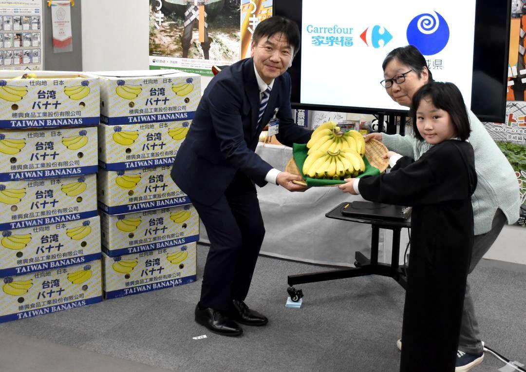 県営業戦略部の久保三千雄部長から台湾産バナナを受け取る石井佐智子さんと片山琴音さん(左から)=県庁